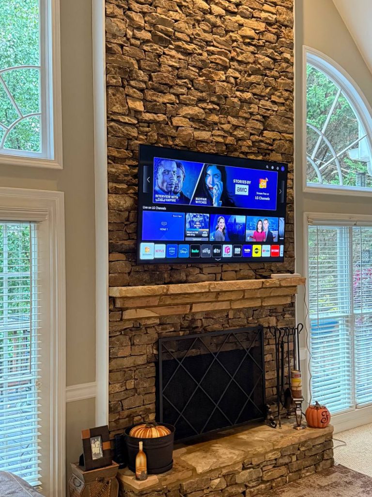 Professional TV wall mounting on a grey textured accent wall with LED lighting by TV Mount Company.